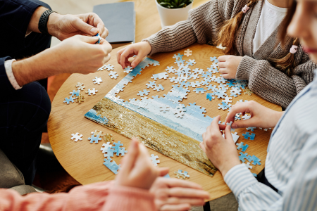 Hands assembling a puzzle,with pieces spread out