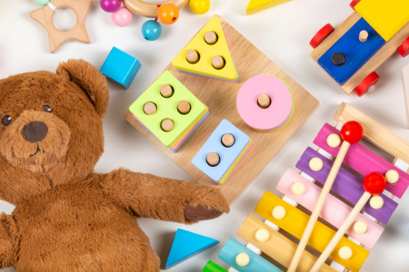smiling child surrounded by colourful blocks, balls and plastic toys